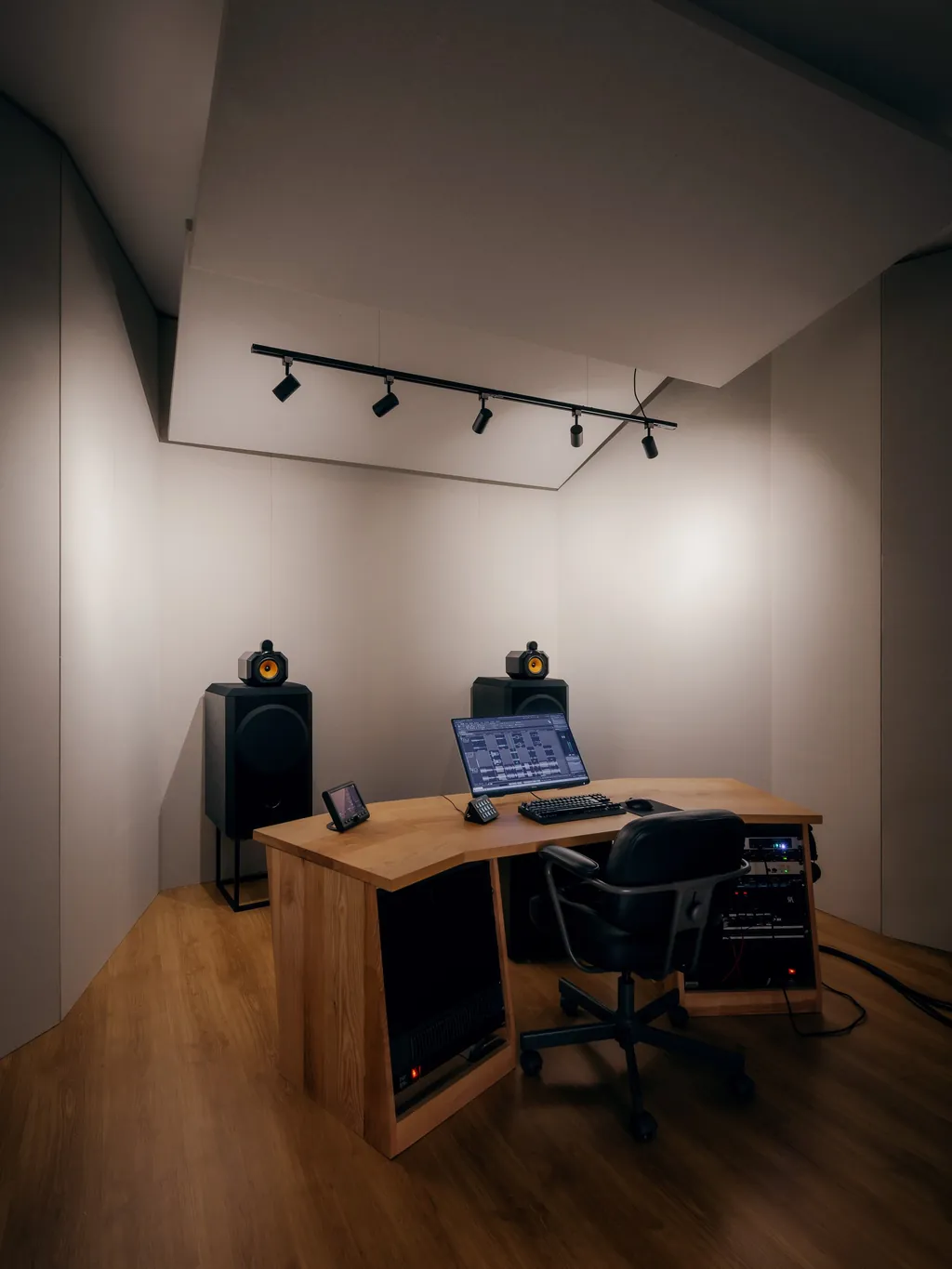 Sala de masterização vista do canto, com tratamento acústico e iluminação