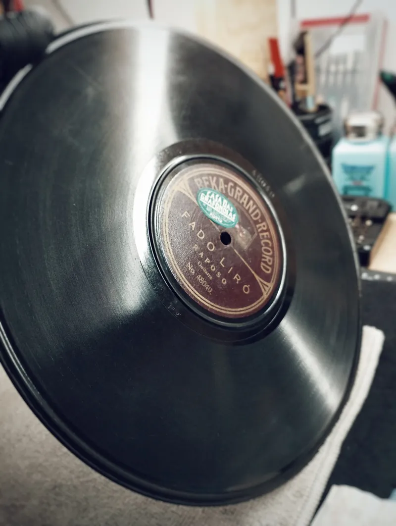 Mão com luva a segurar um disco, com os sulcos a refletir a luz