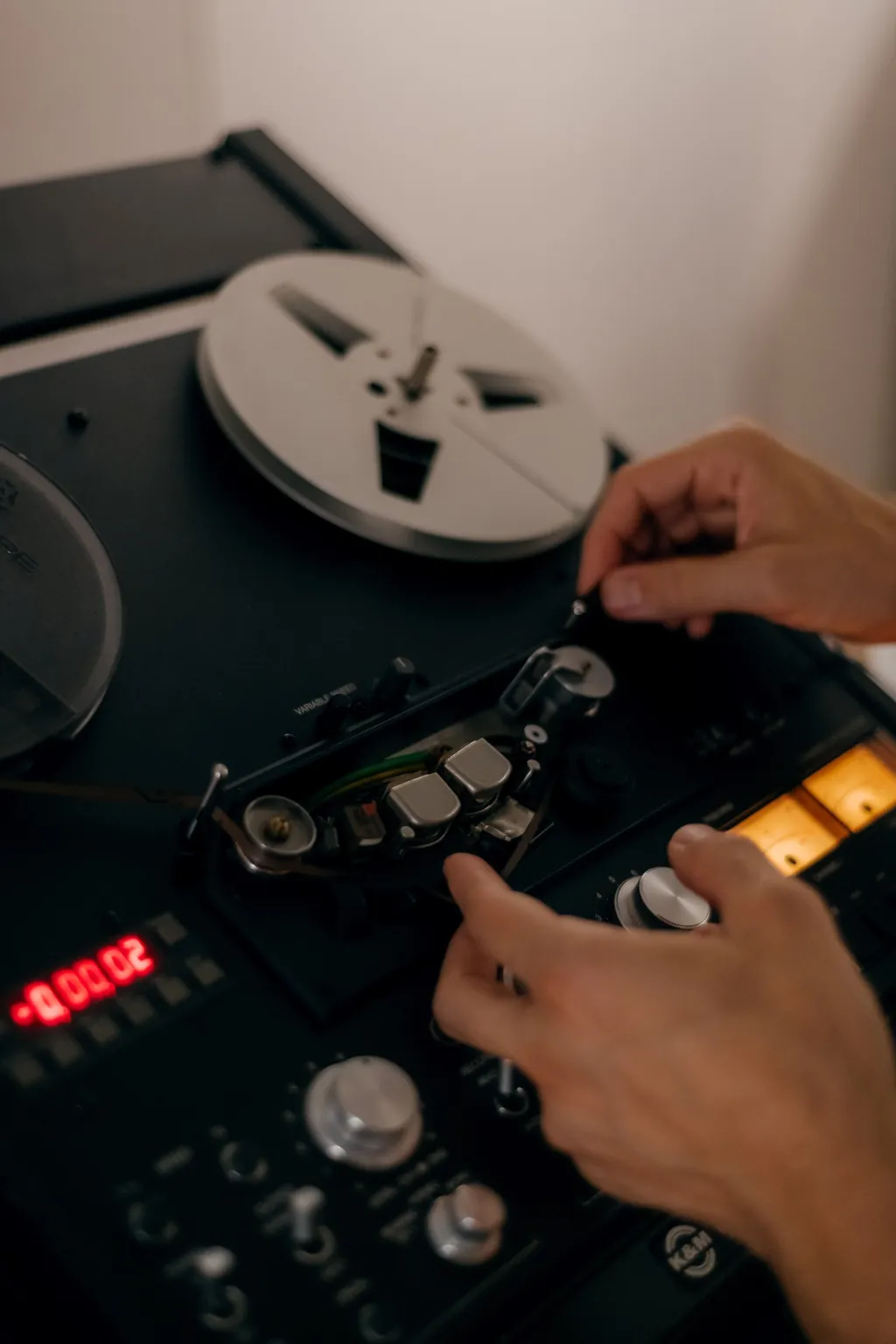 Hands operating a reel-to-reel tape machine during a transfer